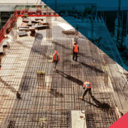 Aerial view of construction workers in safety vests and hard hats installing a dense steel rebar grid