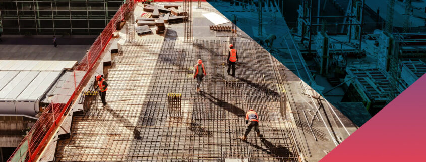 Aerial view of construction workers in safety vests and hard hats installing a dense steel rebar grid